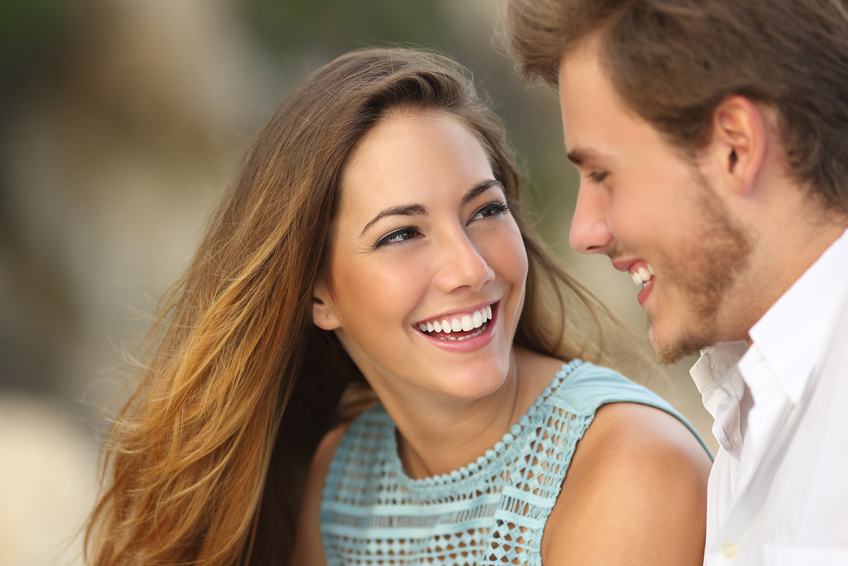Funny couple laughing with a white perfect smile and looking each other outdoors with unfocused background, cfs magazine